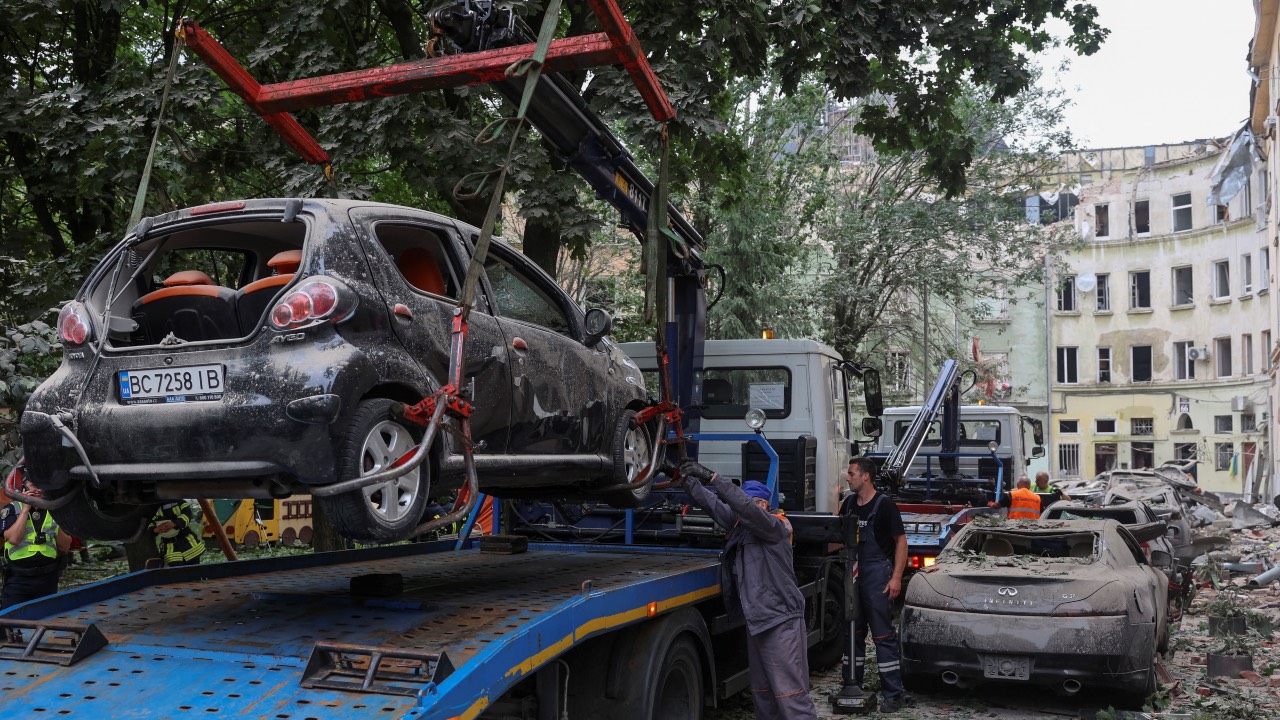 Municipal workers remove damaged cars at a site of a residential building hit by a Russian missile strike in Lviv, Ukraine. /Roman Baluk/Reuters