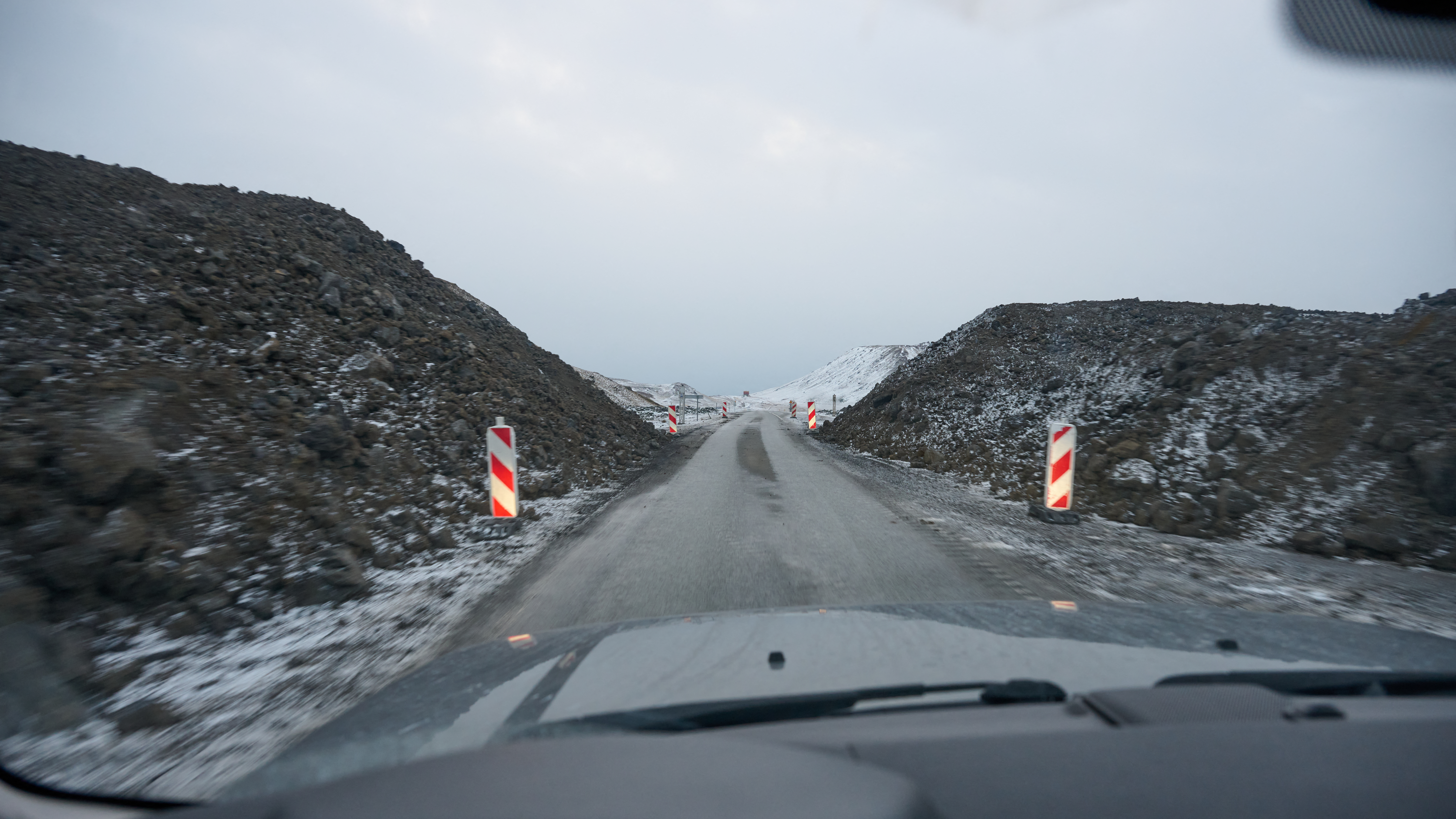 Traffic passes through a gap in a newly built defense wall around the landmark thermal sea water bath, the Blue Lagoon and power plant Svartsengi near Grindavik, western Iceland. /Halldor Kolbeins/AFP