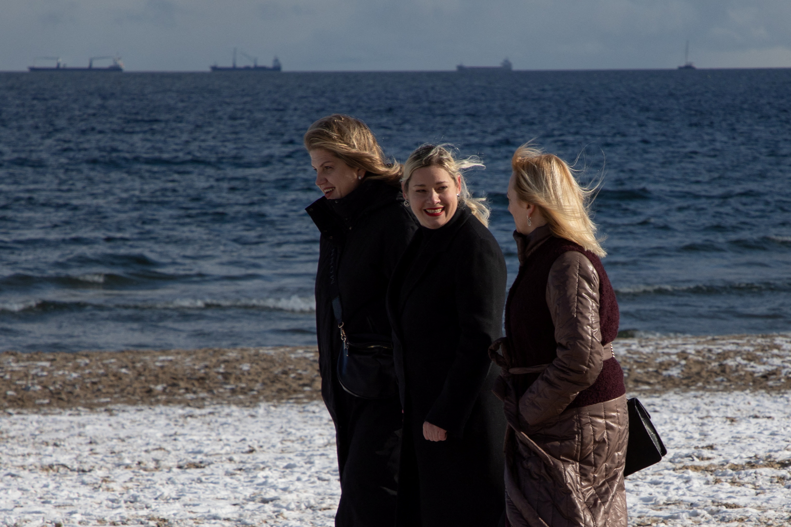 Refugees Olha Shkapa, 45, Oksana Sapronova, 41, and Olena Matviichuk, 50, who fled Ukraine, walk on a snow-covered beach. /Reuters